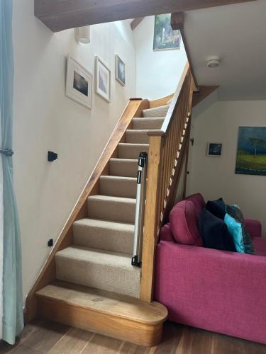 a staircase in a house with a pink couch at Luxury Three Bedroom Barn Conversion in Devon in Hemyock