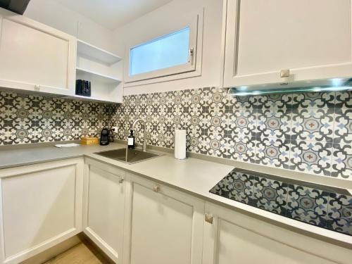 a kitchen with white cabinets and tiles on the wall at Mazzini 34 Collection in Florence