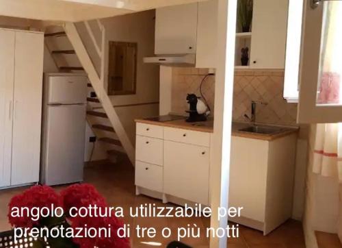 a kitchen with white cabinets and a spiral staircase at Mini Loft Porto Torres in Porto Torres