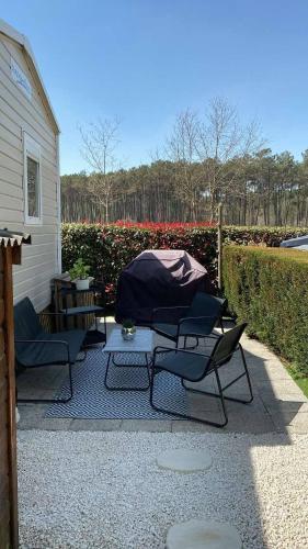 une terrasse avec 3 chaises, une table et une clôture dans l'établissement le m130, à Bias