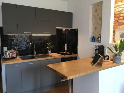 une cuisine avec des placards gris et un comptoir en bois dans l'établissement Very central Toulouse apartment, à Toulouse