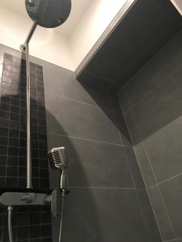 La salle de bains est pourvue d'une douche et d'un mur carrelé noir. dans l'établissement Very central Toulouse apartment, à Toulouse