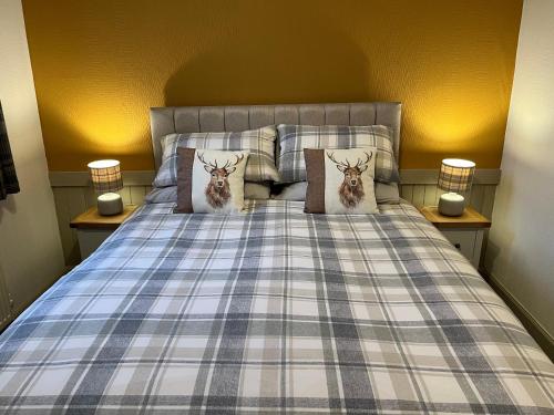 a bed with two deer pillows on it at Belmont Chapel Cottage in Acharacle