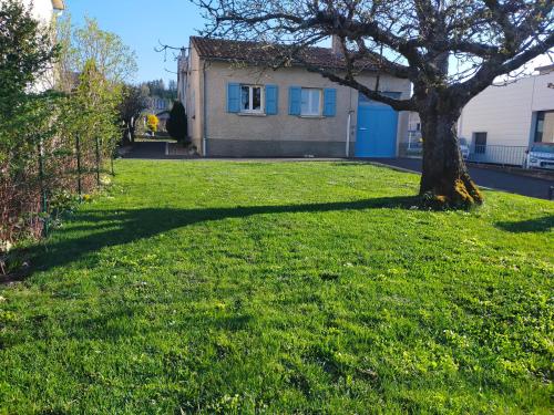 une cour verdoyante avec un arbre et une maison dans l'établissement Chez Tata Malou - Maison avec jardin, cour fermée, proche toutes commodités, à Saint-Julien-Chapteuil
