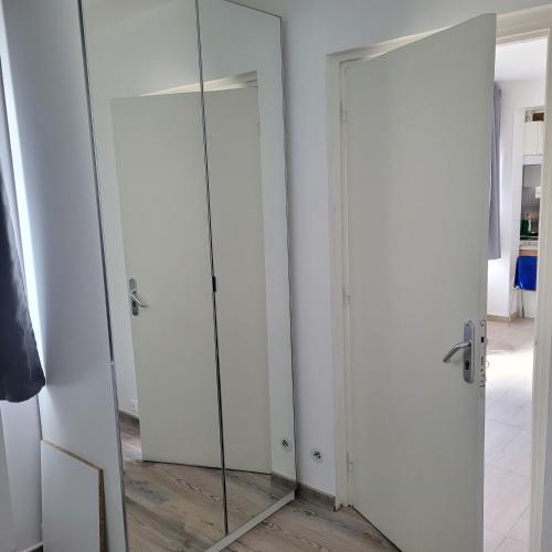 - une porte en verre avec un miroir dans la chambre dans l'établissement Maison pour 4 personnes à 2 pas de Paris, à Bondy
