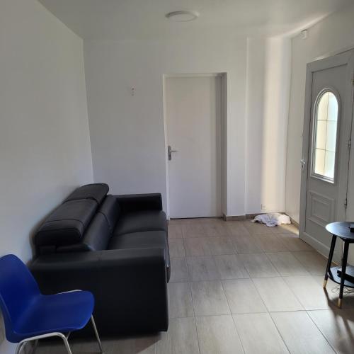 un salon avec un canapé noir et un fauteuil bleu dans l'établissement Maison pour 4 personnes à 2 pas de Paris, à Bondy