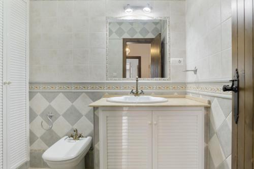 a bathroom with a sink and a toilet and a mirror at Casa Huerta 1 in Conil de la Frontera