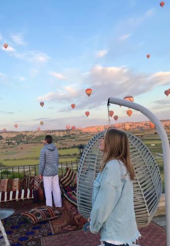a woman standing on a swing looking at hot air balloons at Mesken Cave Suites in Nevsehir