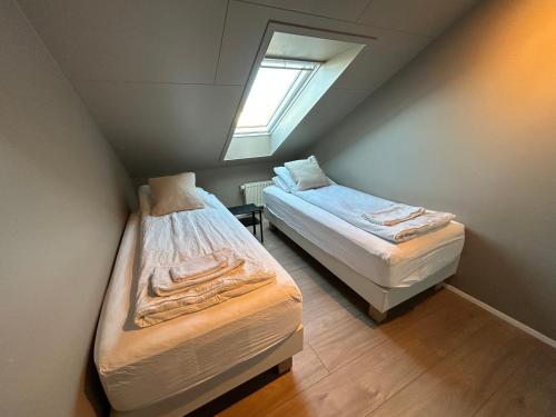 a attic room with two beds and a window at G10 Apartments in Akureyri