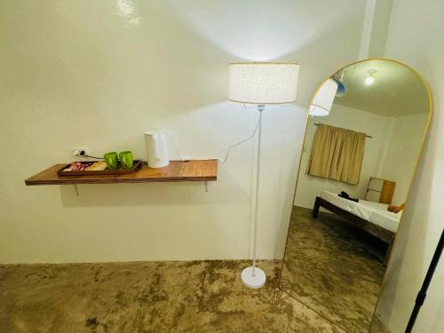 een kamer met een spiegel, een lamp en een tafel bij Fazzah De Siargao in General Luna