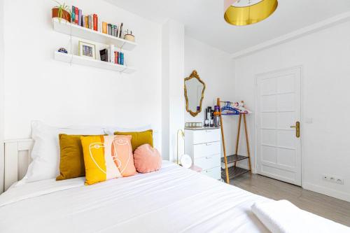 - une chambre avec un lit blanc et des oreillers colorés dans l'établissement GuestReady - Charm & Comfort near Canal St Martin, à Paris