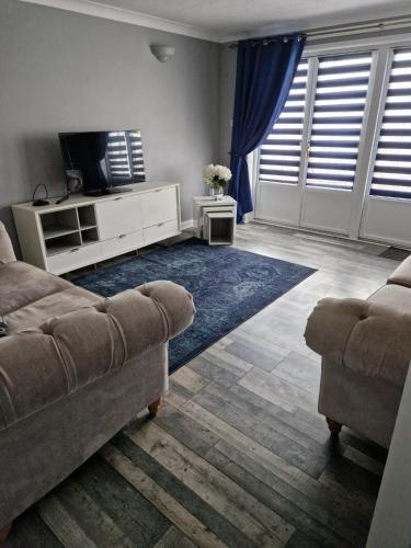 a living room with a couch and a tv at The Cottage in Kirk of Shotts