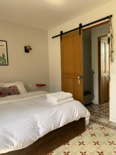 - une chambre avec un lit blanc et une porte en bois dans l'établissement Charmante Maison avec terrasse , Clim , Wifi, à Saint-Rémy-de-Provence
