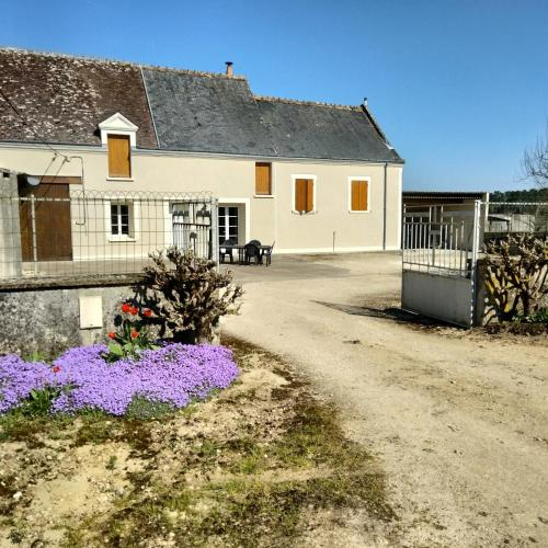 une maison blanche avec des fleurs violettes devant elle dans l'établissement Maison dans les vignes - proche Chenonceau Beauval, à Saint-Georges-sur-Cher