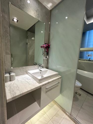 a bathroom with a sink and a mirror and a toilet at Benz Hotel in Zhongli