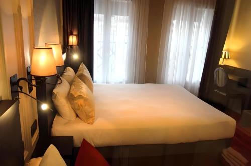 a bedroom with a bed with white sheets and pillows at Hôtel Le Montmartre Saint Pierre in Paris
