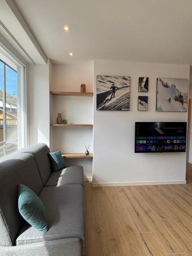 a living room with a couch and a tv on a wall at Appartamenti TEI Orobic Experience in Premana