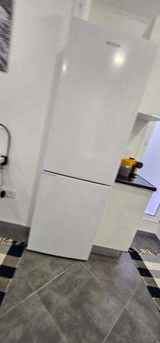 ナザレにあるApartamento Cavaleiroのタイルフロアの客室で、白い冷蔵庫が備わります。