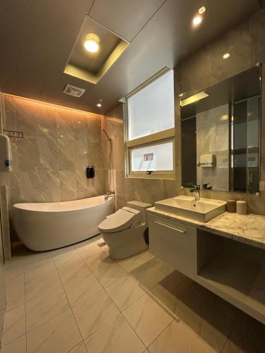 a bathroom with a tub and a toilet and a sink at Benz Hotel in Zhongli