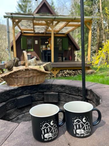 two coffee cups sitting on a table in front of a house at Kerekerdő Apartman - Szarvaskő in Szarvaskő