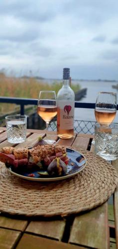 a table with a plate of food and two glasses of wine at Plassenzicht Logies & Sloepverhuur in Loosdrecht
