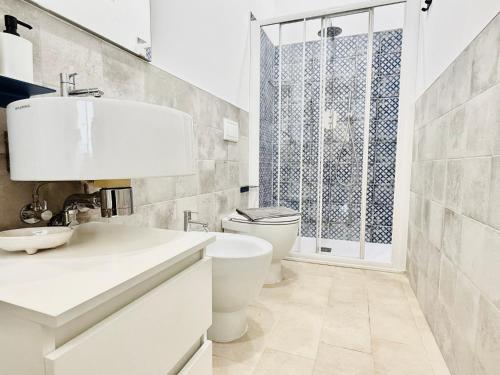 a white bathroom with a toilet and a sink at La casa di Tina in Pachino