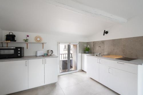 une cuisine blanche avec des armoires blanches et un micro-ondes dans l'établissement Beaux Arts Proche Tram et Corum Climatisation Quartier Bohème, à Montpellier