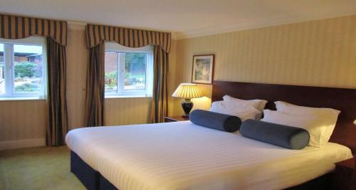 a hotel room with a large bed with two pillows at Windmill Village Hotel, Golf Club & Spa, BW Signature Collection in Coventry