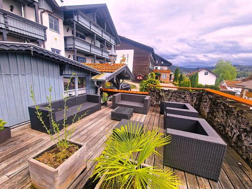 a patio with chairs and plants on a wooden deck at Pension Landhaus Koller - Adults only in Bodenmais