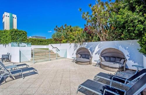 a group of lounge chairs sitting next to a wall at Mantra Legends Hotel in Gold Coast