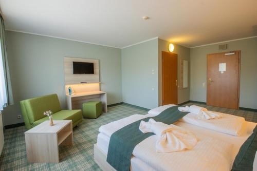 a hotel room with two beds and a chair at Ferien Hotel Spree-Neisse in Neuhausen