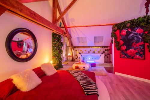 Cette chambre comprend un lit avec une couverture rouge et un miroir. dans l'établissement Love Room Cathédrale Amiens SPA Parking, à Amiens