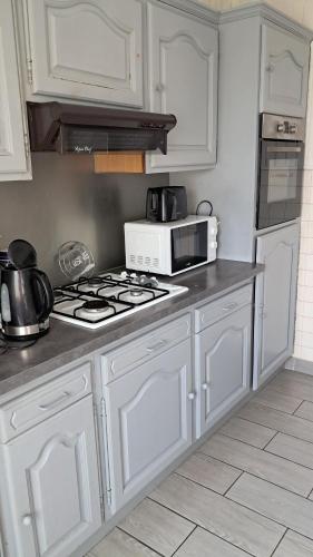 une cuisine avec des armoires blanches et un four à plaques de cuisson dans l'établissement Bienvenue, à Marly