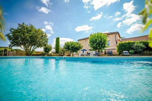 une piscine avec de l'eau bleue devant une maison dans l'établissement Villa Thun - Piscine - Maison de caractère au milieu des vignes, à La Celle-sous-Gouzon
