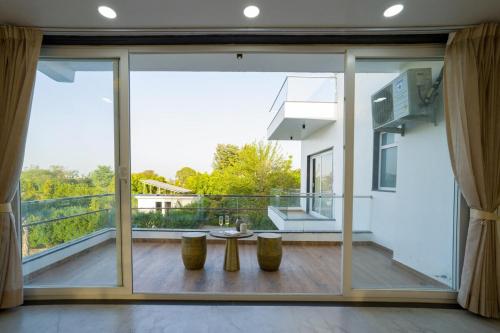 a large glass door with a table and a balcony at ELIVAAS AdhiVa 5-BHK Farmhouse with Private Pool, Bar & Lush Garden in Bahora