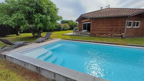 une piscine avec deux chaises et une maison dans l'établissement Superbe Maison Ossature Bois avec Piscine au Calme, à Port-de-Lanne