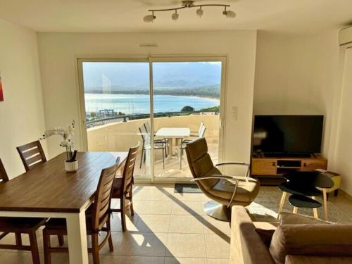 ein Wohnzimmer mit einem Esstisch und Meerblick in der Unterkunft Bel appartement vue mer-montagne in Calvi
