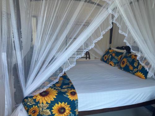 a bed with a canopy with sunflower pillows on it at Royal Palace Mirissa in Mirissa