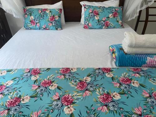 a bed with blue and pink floral sheets and pillows at Royal Palace Mirissa in Mirissa