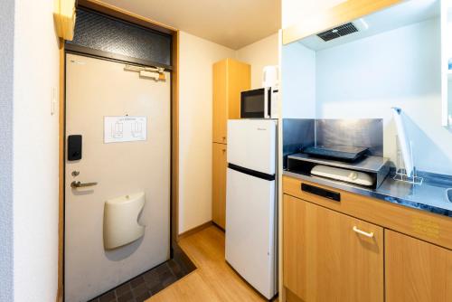 a small kitchen with a refrigerator and a microwave at Otani gofuku in Fukuoka