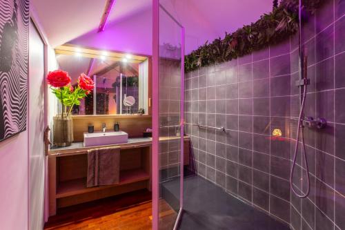 ein Badezimmer mit einem Waschbecken und einer Dusche mit lila Beleuchtung in der Unterkunft Suite Romantique 45m2-Amiens Centre-SPA & Parking in Amiens