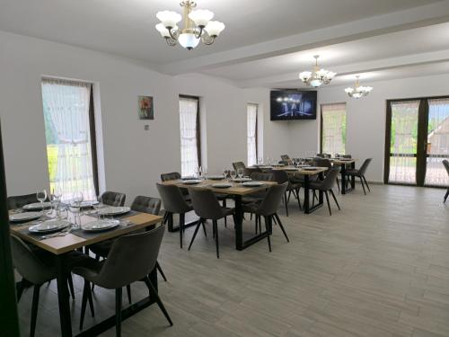 a dining room with tables and chairs and a television at Pensiunea Turistică La Tei in Bistricioara