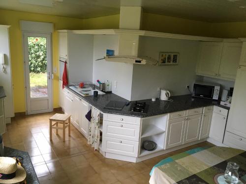 une cuisine avec des armoires blanches et un comptoir noir dans l'établissement Plages & GR 10 min à pied - grande maison calme, à Plougasnou