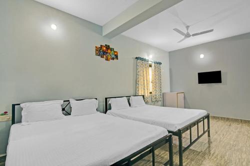 two twin beds in a room with a tv at Hotel O Sai Leela in Goa