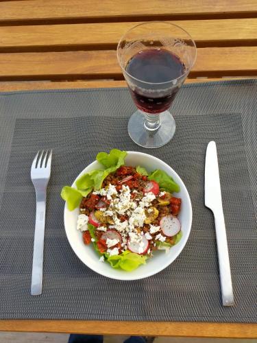 a plate of salad and a glass of wine on a table at Au Ptit bonheur in Grignon
