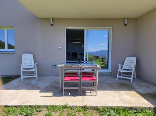 d'une terrasse avec 2 chaises, une table et une fenêtre. dans l'établissement Grand F2 vue montagne, à Olmeta-di-Tuda