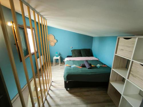 une chambre avec un lit et un mur bleu dans l'établissement Havre de Paix avec Jardin privatif et Parking Gratuit à 15 min de Versailles, à Montigny-le-Bretonneux