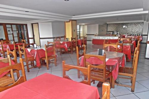 a restaurant with tables and chairs with red tables and chairs at Hotel Subaé in Feira de Santana