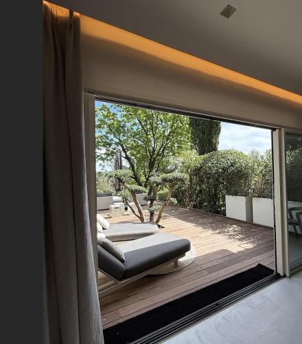 une pièce avec une grande fenêtre avec deux chaises sur une terrasse dans l'établissement One Palm, à Grimaud