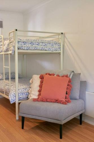a bedroom with bunk beds and a chair with a pillow at The Blue House - 200m from Point Roadknight Beach in Anglesea